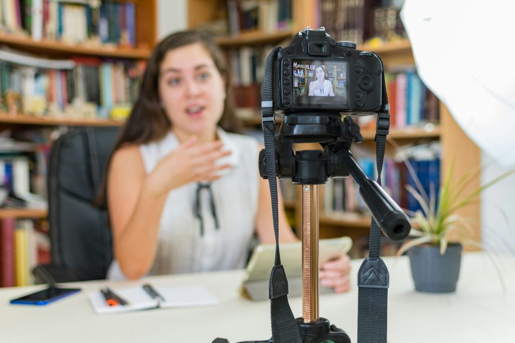 Young Caucasian female vlogger making a video with a DSLR camera at home